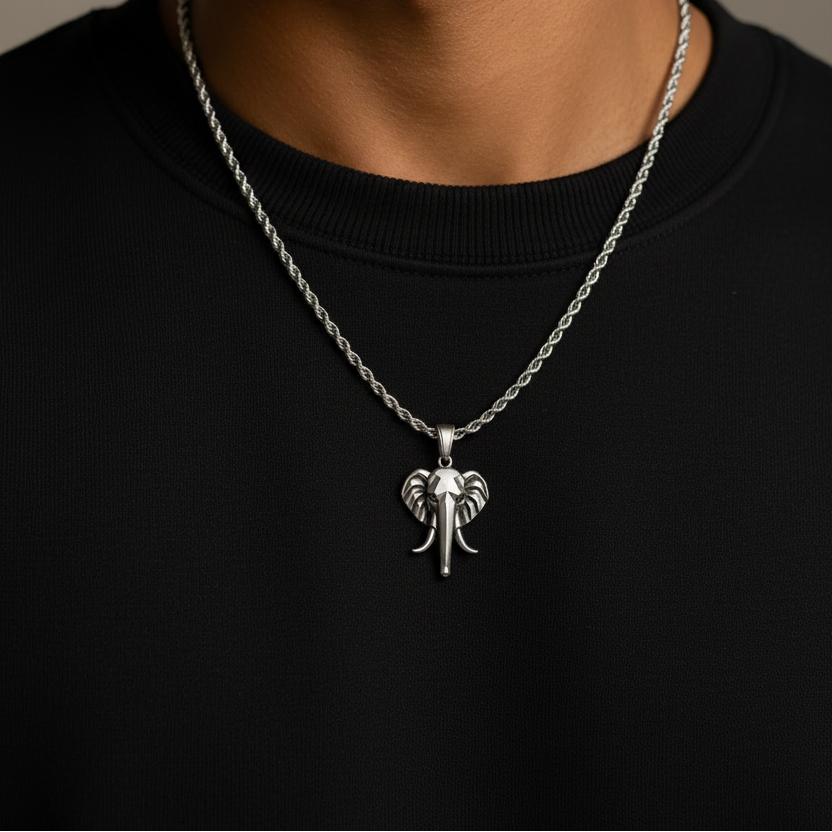 Man wearing a silver necklace with an elephant pendant on a neutral background
